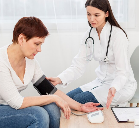 female doctor measuring blood pressure of female patient with short hair for PVD treatment